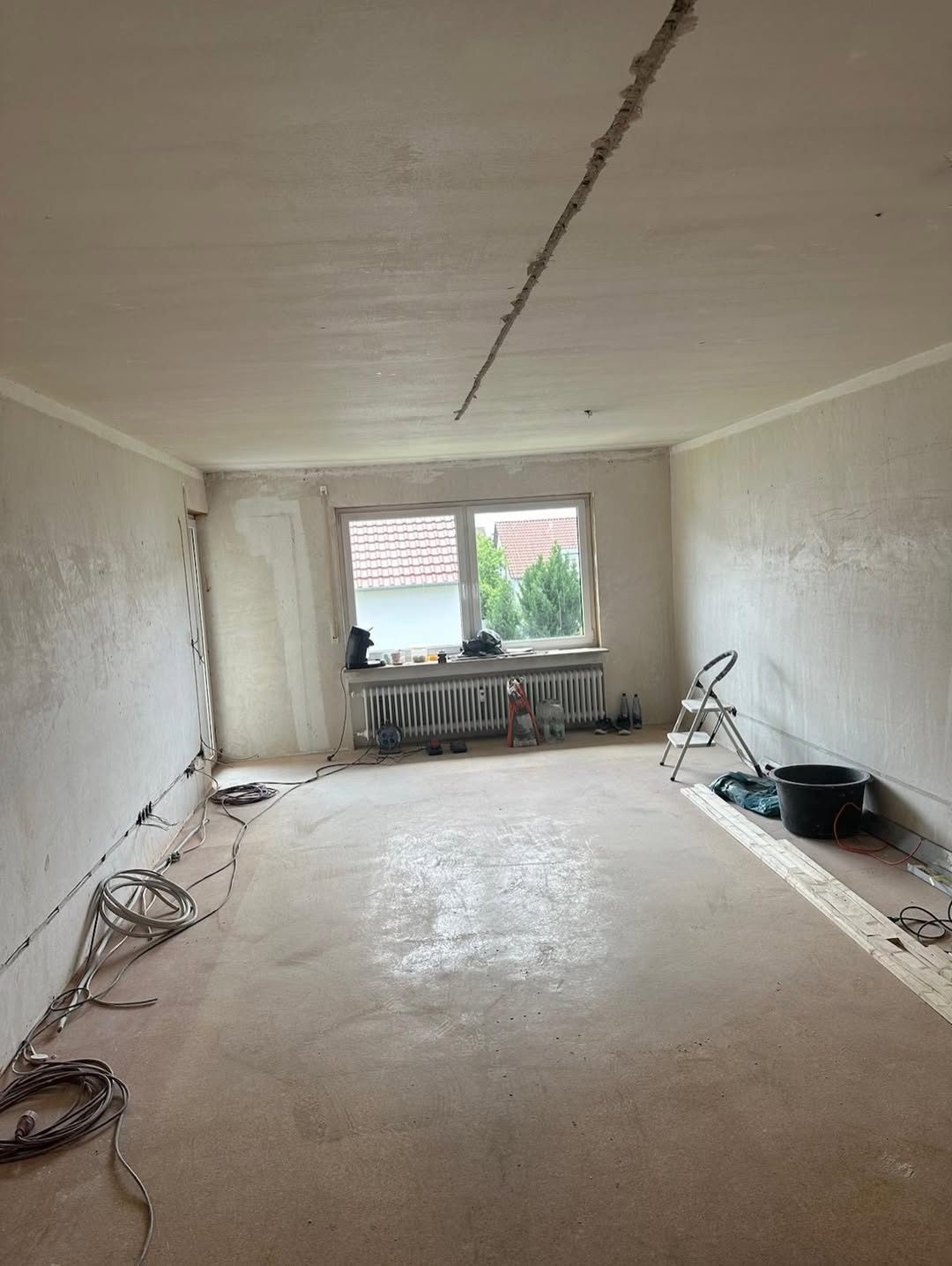 Wohnzimmer vor der Renovierung — Risse in der Decke, freiliegende Kabel, Estrich